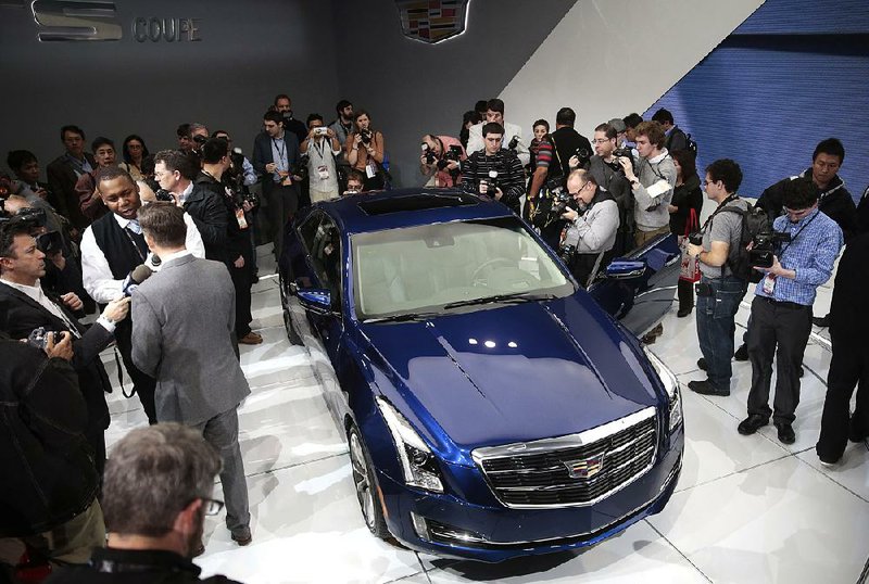 Reporters look at a 2015 Cadillac ATS at the 2014 North American Auto Show in Detroit last month. GM on Thursday reported a quarterly profit of $913 million. 