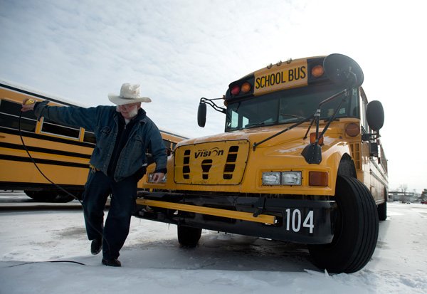 Dale Shouse, bus driver for the Springdale School District, unpluggs the block heater to his bus Thursday, Feb. 16, 2014 during his pre-trip check at the district's bus yard off Emma Avenue in Springdale. Shouse runs routes to Hunt Elementary and Har-Ber High School. The recent winter weather has left snow and ice on many of the side streets that has altered some bus routes.