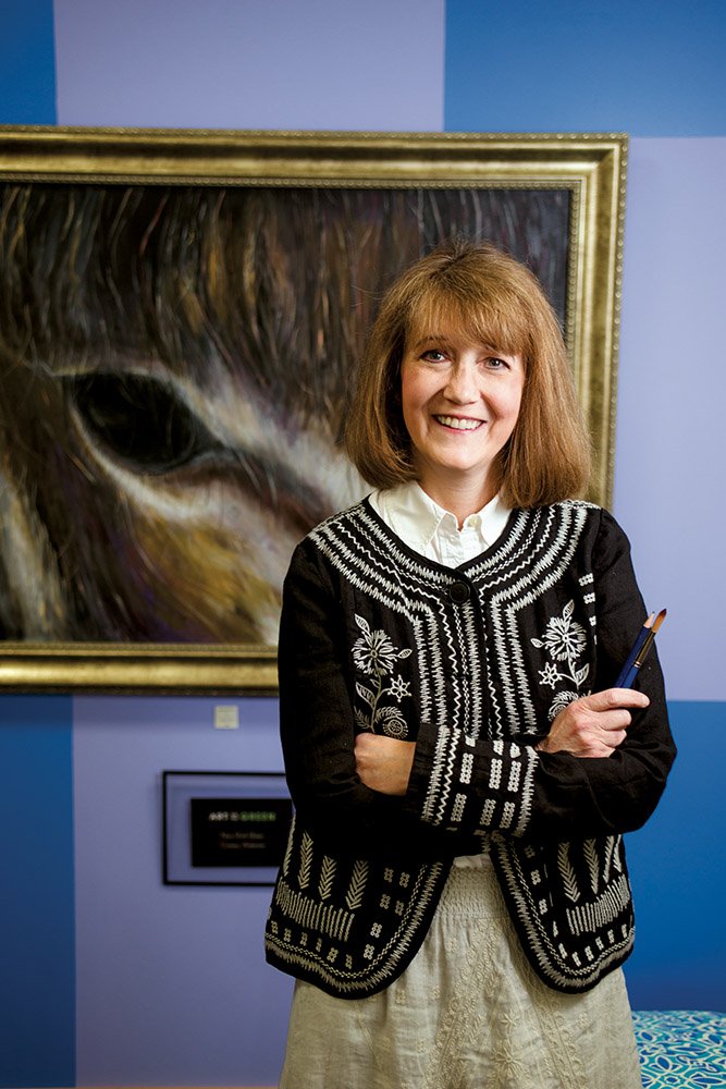 Nina Baker of Conway stands in front of a painting she did of one of her donkeys. She and her husband, Dr. David Baker, opened Art on the Green gallery about six months ago on Bob Courtway Drive in Conway. Nina, 52, has been painting since she was a child and said a doctor told her when she was about 12 that she would probably go blind, but her eyesight stabilized.