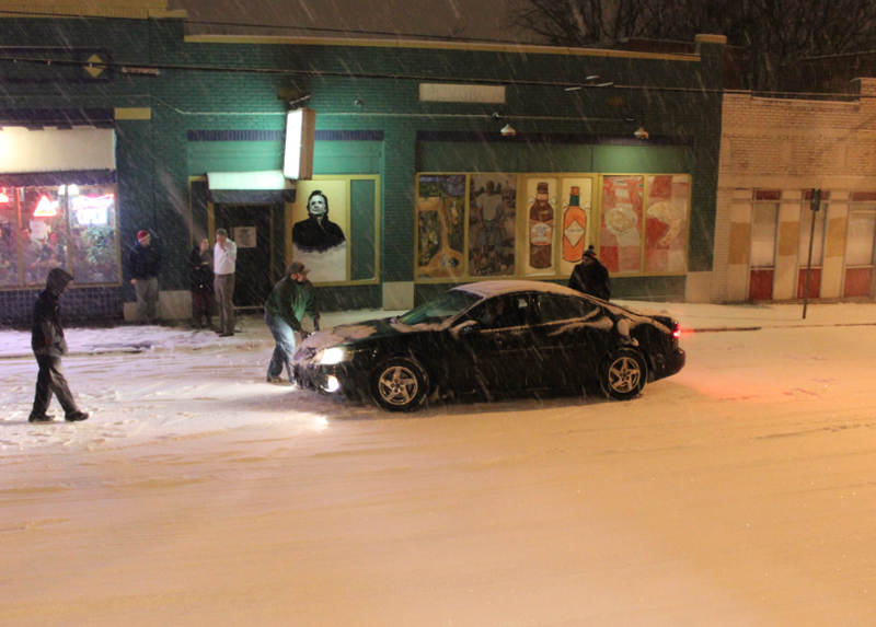 Motorists try to push free a car that got stuck in snow on Markham Street near Kavanaugh Boulevard Friday night.