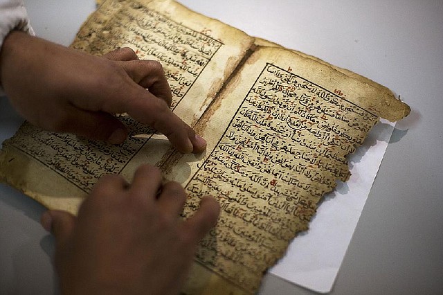 An employee (top photo) works on a restoration of an old manuscript at the al-Aqsa mosque library in Jerusalem.