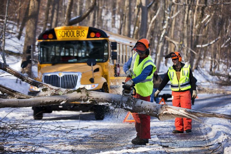 Workmen clear a downed tree blocking a school bus in the aftermath of a winter storm, Friday, Feb. 7, 2014, in Downingtown, Pa. Schools canceling classes because of winter weather in at least 10 states have used up the wiggle room in their academic calendars, forcing them to schedule makeup days or otherwise compensate for the lost time. (AP Photo/Matt Rourke)