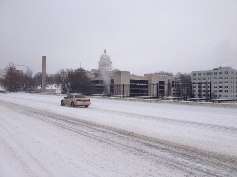 A car moves along a snow-covered Markham Street near the Arkansas state Capitol Saturday morning.