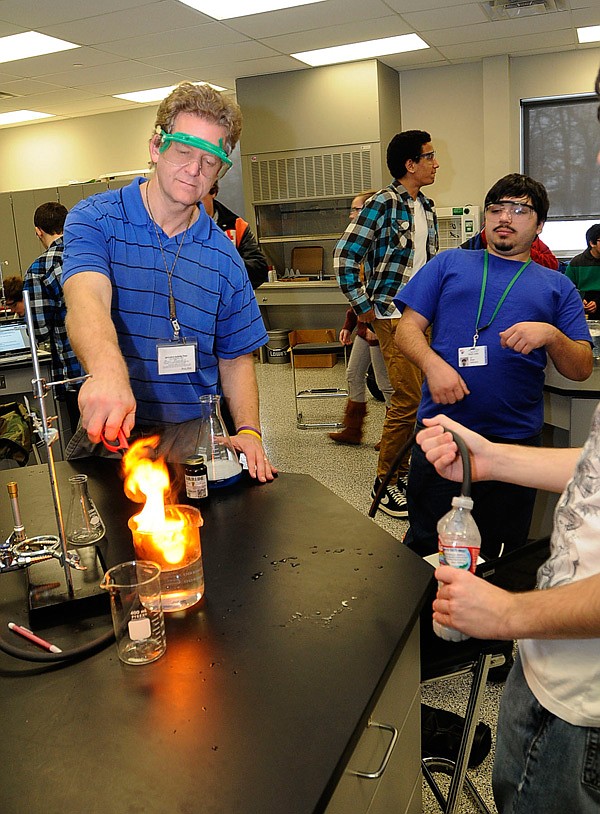 FLAMMABLE GAS 
Mark Morley, a chemistry and physics teacher at Rogers New Technology High School, lights flammable gas on Friday Feb. 7 2014 while student Ari Wright, anticipates an explosion. Students combined different chemicals to produce various flammable gasses in chemistry class on Friday.