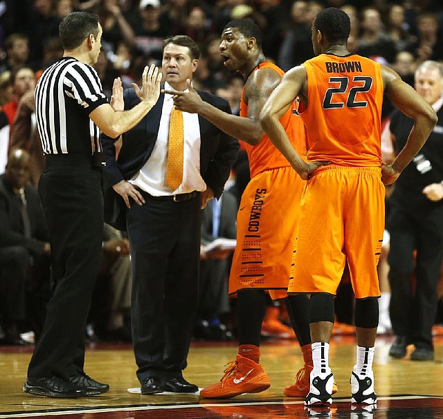 Oklahoma State head coach Travis Ford, center, Marcus Smart and Markel Brown(22) speak to the referee after Smart shoved a fan during a NCAA college basketball game in Lubbock, Texas, Saturday, Feb, 8, 2014. (AP Photo/Lubbock Avalanche-Journal, Tori Eichberger) ALL LOCAL TV OUT