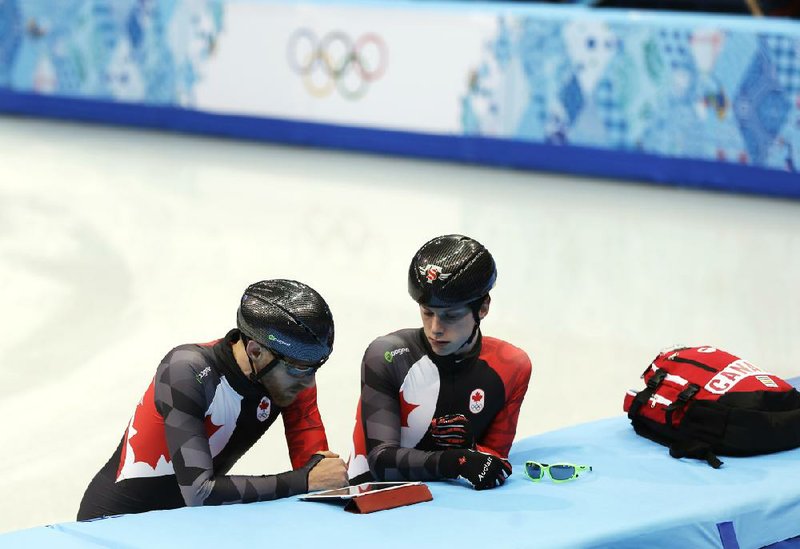 Canada's Jean Olivier, left, and Charle Cournoyer look at a tablet device during a team short track speed skating training session at the Iceberg Skating Palace ahead of the 2014 Winter Olympics, Tuesday, Feb. 4, 2014, in Sochi, Russia. (AP Photo/Mark Baker)
