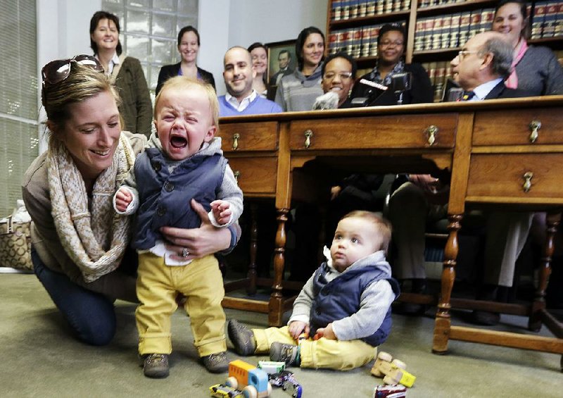 Amanda Broughton, left, comforts one of her two twin sons while her partner Michele Hobbs, top left, stands behind her Monday, Feb. 10, 2014, during a news conference in Cincinnati. Four legally married gay couples filed a federal civil rights lawsuit Monday seeking a court order to force Ohio to recognize same-sex marriages on birth certificates despite a statewide ban. Broughton is the birth mother of the twins. (AP Photo/Al Behrman)