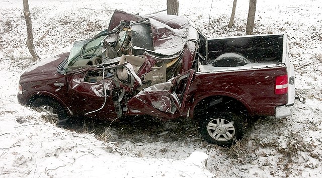 Police Photo by Scott Gillming Though pretty much hidden from view, a Gravette rescue worker reaches into the smashed cab of a pickup truck to assist the driver, following an accident in which the eastbound truck left the roadway and rolled on its descent to the bottom of Old Town Park on Sunday, Feb. 2.