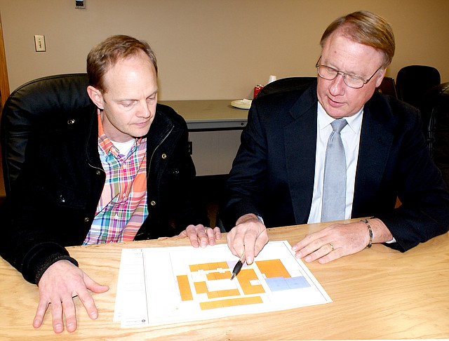 Photo by Dodie Evans Richard Page, Gravette superintendent of schools (right), and facilities committee member Bryan Johnson look over a revised floor drawing of an elementary school being considered at Bella Vista. It was presented at a meeting of the committee Monday afternoon. Architects have reduced the building from 68,000 square feet to the board s requested 61,000 square-foot structure.