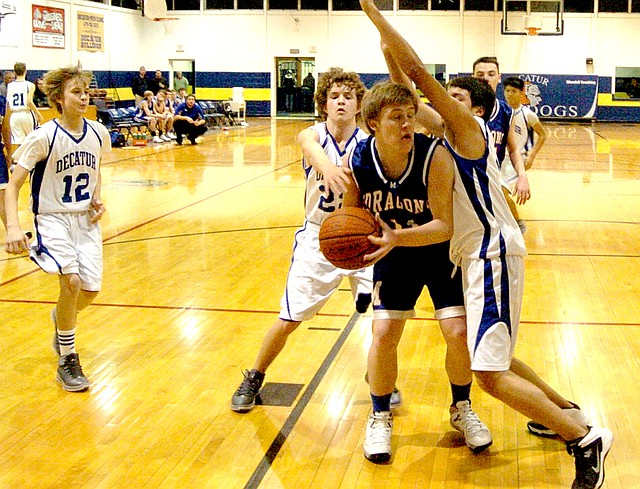 Photo by Mike Eckels Decatur s Ryan Shaffer (#22) and Jaffett Puga (#30 turn sideways on right) block a Mountainburg player from shooting the ball while Bracey Owens (#12) sets up to cut off the players escape. The Bulldog junior high boys lost to the Dragons 24 to 20 Feb. 6 at Peterson Gym in Decatur.