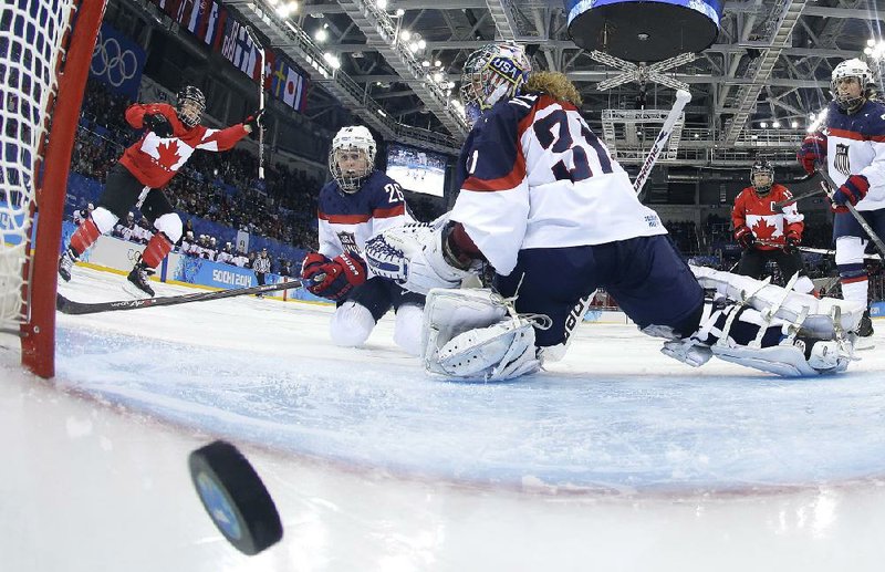 Canada’s Meghan Agosta-Marciano (left) celebrates a goal in a 3-2 victory as U.S. goalkeeper Jessie Vetter (right) and teammate Kendall Coyne (26) watch the shot Wednesday. The teams are favored to meet in the gold medal game. 