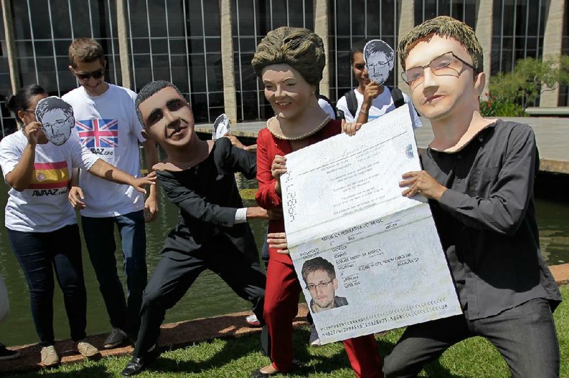 Activists wearing masks of former NSA analyst Edward Snowden, right, Brazil's President Dilma Rousseff, center, and President Barack Obama perform with an oversized passport outside the foreign ministry to demand Snowden be granted asylum in Brasilia, Brazil, Thursday, Feb. 13, 2014.  Last year, Snowden revealed that the United States collected data on billions of telephone and email conversations in Latin America's biggest country, including Rousseff's communications with aides. (AP Photo/Eraldo Peres)