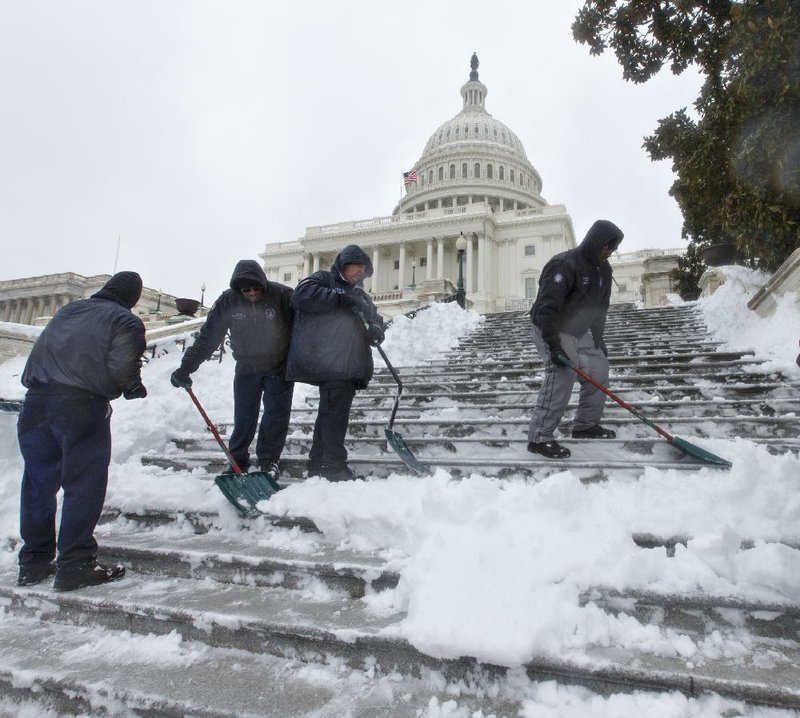 Workmen clear snow from the steps on Capitol Hill in Washington, Thursday, Feb. 13, 2014, as winter weather shut down Washington. After pummeling wide swaths of the South, a winter storm dumped nearly a foot of snow in Washington as it marched Northeast and threatened more power outages, traffic headaches and widespread closures for millions of residents. (AP Photo/J. Scott Applewhite)