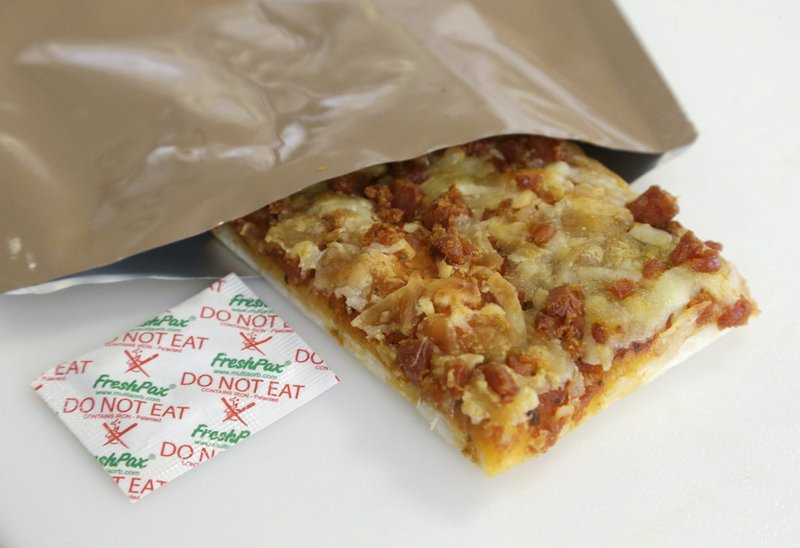 A slice of prototype pizza, in development to be used in MRE's — meals ready to eat, sits in a packet next to a smaller packet known as an oxygen scavenger, left, at the U.S. Army Natick Soldier Research, Development and Engineering Center on Thursday, Feb. 6, 2014, in Natick, Mass. Pizza is in development to be used in individual field rations known as meal ready to eat, or MREs. It has been one of the most requested options for soldiers craving a slice of normalcy in the battlefield and disaster areas. 