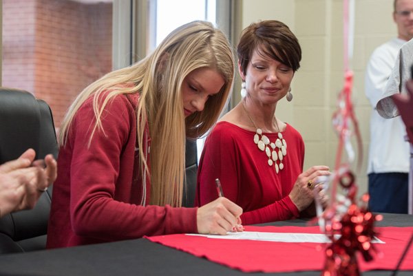 Payton Stumbaugh, Springdale Har-Ber senior track athlete, signs a national letter Friday, Feb. 14, 2014 as her mother Christina Stumbaugh looks on at a ceremony at the school in Springdale. Stumbaugh was joined at the table by her mother, father and sister as she signed to run for the University of  Oklahoma in Norman, Okla.