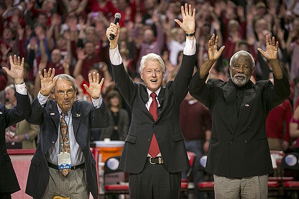 Eddie Sutton, left, former President Bill Clinton, center, and Nolan Richardson, right, call the "Hogs" during halftime of an NCAA college basketball game between Arkansas and LSU on Saturday, Feb. 15, 2014, in Fayetteville, Ark. (AP Photo/Gareth Patterson)