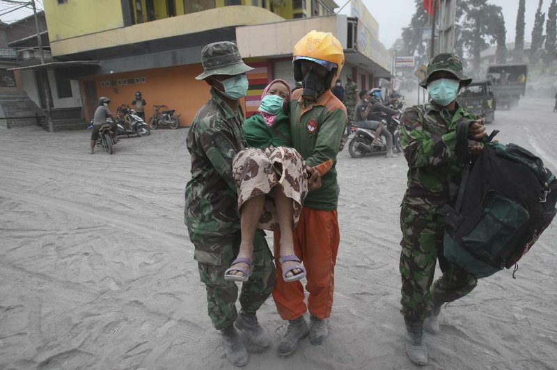 Soldiers and rescuers on Indonesia’s Java Island evacuate a woman Saturday in the aftermath of Thursday’s eruption of Mount Kelud. Cleanup began Saturday. The eruption killed four people and displaced more than 56,000, but Indonesians are scooping up the ash, which is prized as fertilizer. 