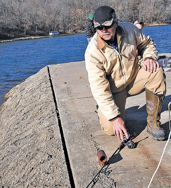  STAFF PHOTO FLIP PUTTHOFF 
Jeff Overturf checks his fishing rod Friday hoping to catch some trout at Lake Atalanta in Rogers. The Arkansas Game & Fish Commission stocks the lake with trout each winter.