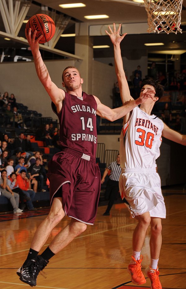 STAFF PHOTO ANDY SHUPE

Dylan Gray, Siloam Springs senior, shoots ahead of Rogers Heritage senior Austin Prince on Jan. 31. Gray hit a dramatic last-second shot Friday to stun Springdale High and is this week’s 7A/6A-West Conference Boys Player of the Week.