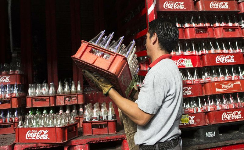 A worker loads empty Coca-Cola bottles into a delivery truck in Mexico City in this file photo. Sales volume in Coca-Cola’s Latin America division was little changed in the fourth quarter, the company said Tuesday. 