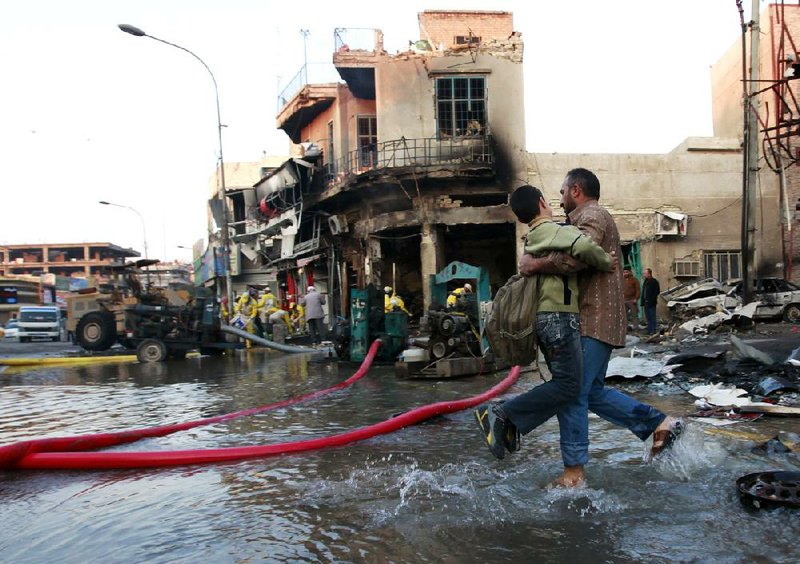 An Iraqi helps his school-bound son past the scene of a car-bomb attack Tuesday in Baghdad. 