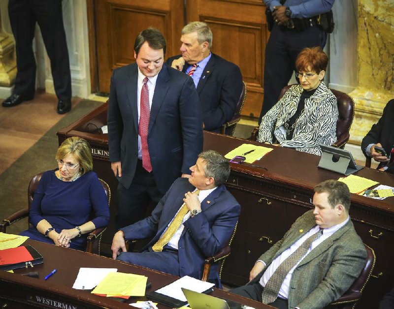 State Rep. John Burris, R-Harrison, (standing) talks with House Majority Leader Bruce Westerman after speaking in favor of continued funding for the expanded, private-option Medicaid plan. Ann Clemmer, R-Benton, (front left) voted no, while Nate Bell, R-Mena, (front right) voted yes. State Reps. Butch Wilkins (back row), D-Bono, and Jody Dickinson, D-Newport, also backed the proposal. 