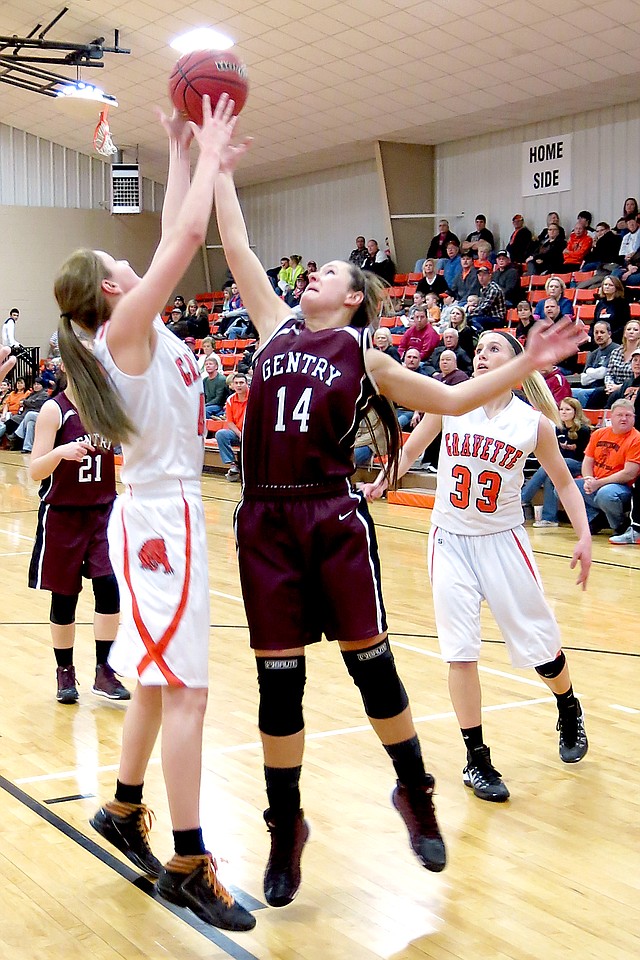 Photo by Randy Moll Gravette s Sydney Hicks and Gentry s Kristen Flesner vie for the rebound during play between the two teams on Feb. 11 at Gravette. Kylee Davis, of Gravette, looks on.