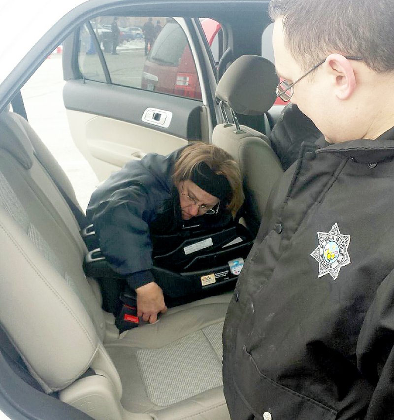 Photograph submitted Pea Ridge Police Cpl. Clela Eggrebrecht and Officer Joey Ferris installed a car seat recently at a car-seat safety event at Walmart in Rogers. The two Pea Ridge Police officers, along with Sgt. Mitch Brown, spent a week learning about car seat safety and are now certified car seat technicians. The three, along with Police Officer Mark Garrison, are the four certified technicians on the Pea Ridge Police Department, and will inspect the installation of a car seat and check for recalls.