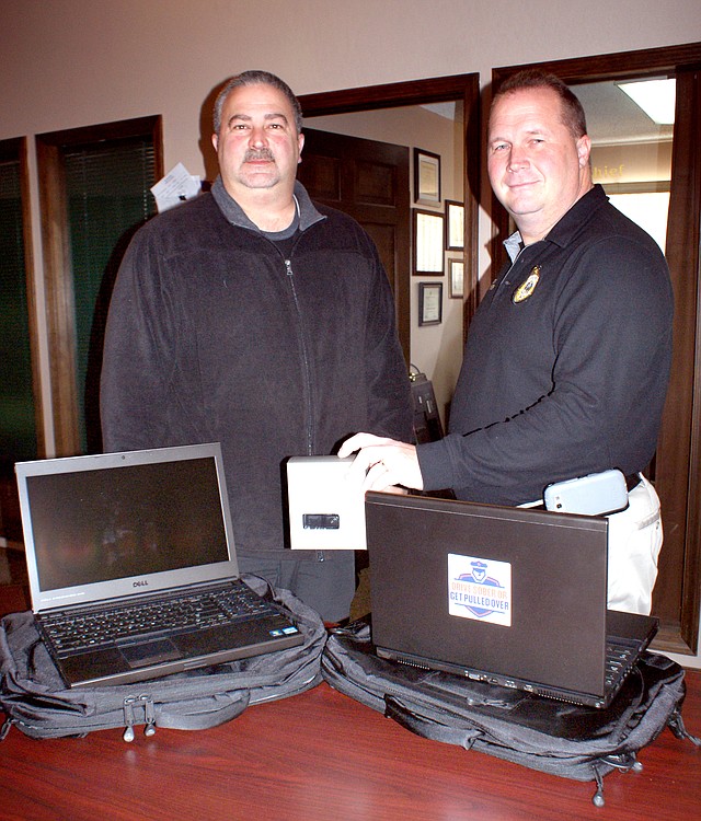 Photo by Dodie Evans Gravette Police Chief Bower, right, and Sgt. Rusterholz show new computers received by the Gravette Police Department. Bower is holding a box which held one of the cameras.