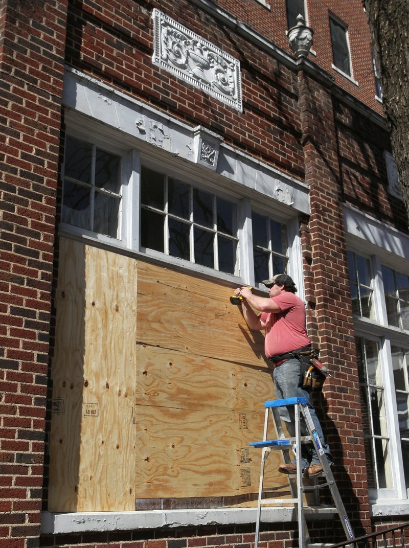 Jared Yarberry Construction employee Tyler Vines screws a piece of plywood over a window at the Majestic Hotel on Monday, February 17, 2014. The company was boarding up all the windows and doors on the building Monday. 