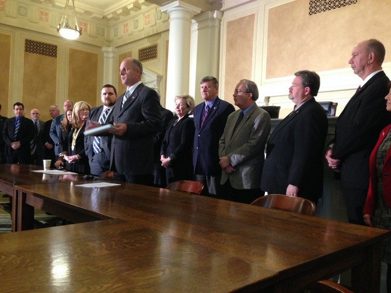 A group of Arkansas legislators led by Sen. Jim Hendren, R-Gravette, center, and Rep. Bob Ballinger, R-Hindsville, to his left, present a bill Wednesday, Feb. 19, 2014, that would set a limit on private-option funding and enrollment after July 1.
