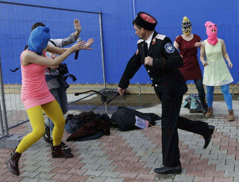 A Cossack militiaman attacks Nadezhda Tolokonnikova and a photographer as she and fellow members of a punk group, including Maria Alekhina (right), stage a protest performance Wednesday in Sochi, Russia. 