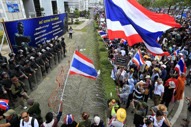 Thai anti-government protesters, led by Suthep Thaugsuban, confront soldiers lined up Wednesday outside the office of Permanent Secretary for Defense, a temporary office of Prime Minister Yingluck Shinawatra on the outskirts of Bangkok, Thailand. 