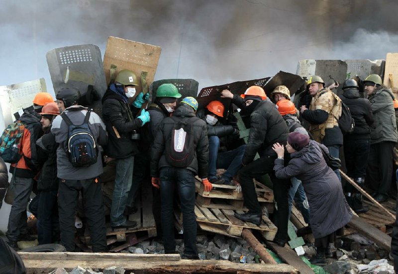 Protesters gather behind shields Wednesday in Kiev’s Independence Square during clashes with Ukrainian riot police. 