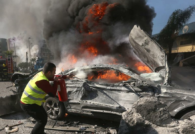 A firefighter tries to extinguish a burning car Wednesday after an explosion outside the Kuwaiti Embassy and Iran’s cultural center on the outskirts of Beirut. 