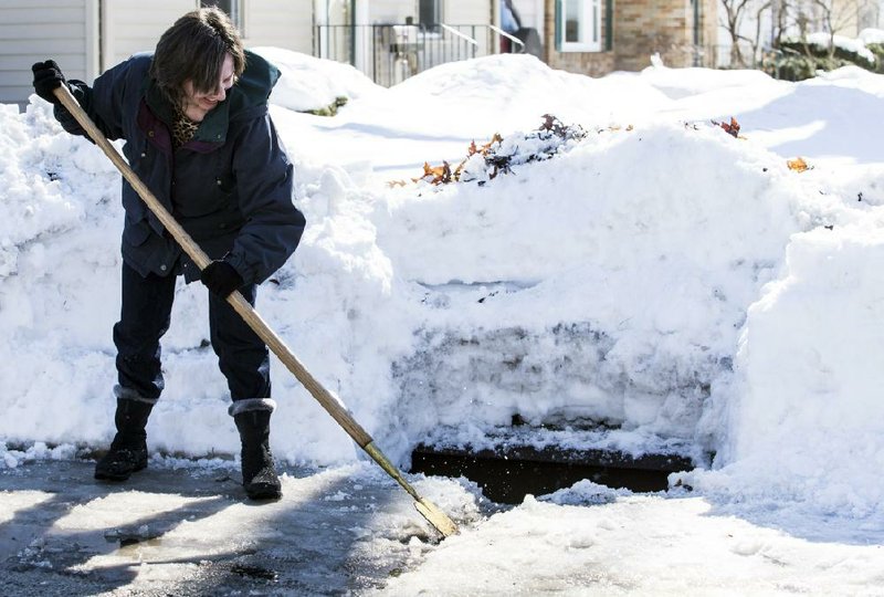 Lynda Remling-Berge opens a path for water to flow down the storm grate Wednesday in Rockford, Ill. A five-woman team cleared out storm grates in their neighborhood to prepare for possible flooding from the melting snow and rain that is predicted for today. 