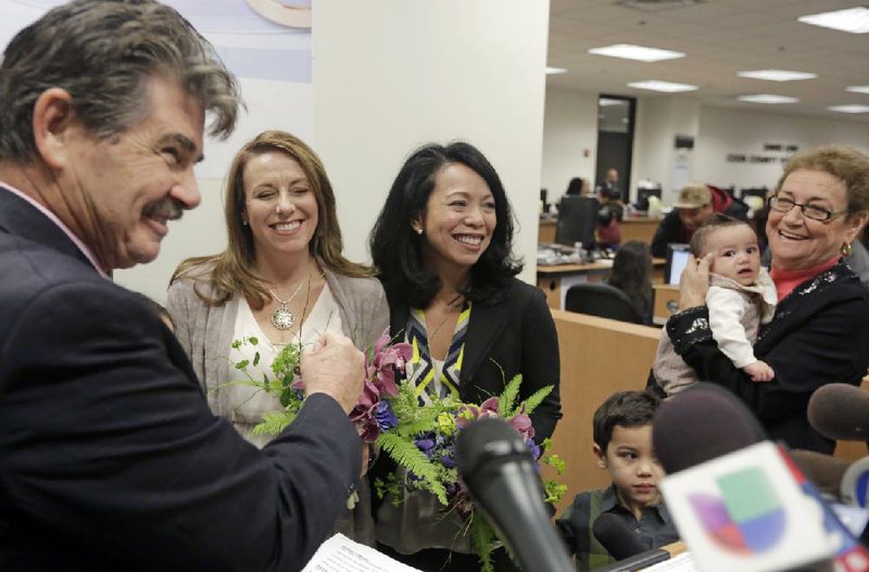 Cook County Clerk David Orr, left, performs a marriage ceremony for Theresa Volpe, second from left, and Mercedes Santos on Friday, Feb. 21, 2014, in Chicago. Same-sex couples in Illinois' Cook County began receiving marriage licenses immediately after a federal judge's ruling Friday that some attorneys could give county clerks statewide justification to also issue the documents right away. (AP Photo/M. Spencer Green)