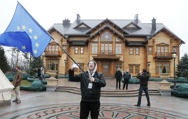 A protester waves an EU flag at the Ukrainian President Yanukovych's countryside residence in Mezhyhirya, Kiev's region, Ukraine, Saturday, Feb, 22, 2014. Viktor Yanukovych is not in his official residence of Mezhyhirya, which is about 20 kilometres north of the capital. Ukrainian security and volunteers from among Independence Square protesters have joined forces to protect the presidential countryside retreat from vandalism and looting. (AP Photo/Efrem Lukatsky)