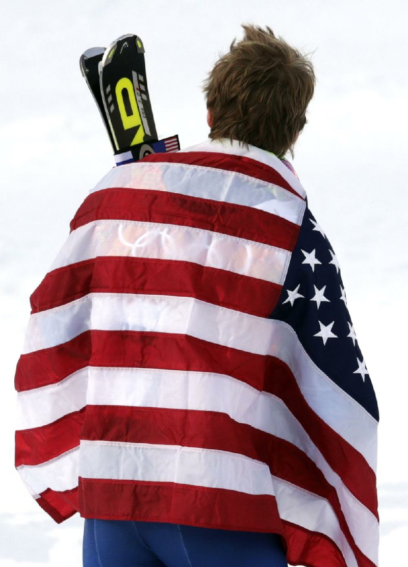 Men's giant slalom gold medalist Ted Ligety of the United States wears the American flag on the podium at the Sochi 2014 Winter Olympics, Wednesday, Feb. 19, 2014, in Krasnaya Polyana, Russia.(AP Photo/Charles Krupa)