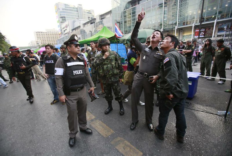 Police officers point to possible evidence at the scene of an explosion at a main protest site in Bangkok, Thailand, Sunday, Feb. 23, 2014. More than a dozen people were hurt Sunday by a small explosion at an anti-government protest in Bangkok, less than a day after a bloodier attack in an eastern province killed one child and left about three dozen people wounded. (AP Photo/Wally Santana)