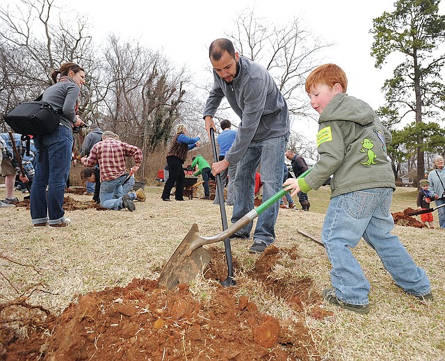 Klint Oxford, 5, right, helps friend Aron Shelton, both of Fayetteville, plant fruit trees Thursday to establish the first community orchard in Fayetteville at the Yvonne Richardson Community Center. The project is the result of a collaboration between Ames Orchard & Nursery and the city Parks and Recreation Department.