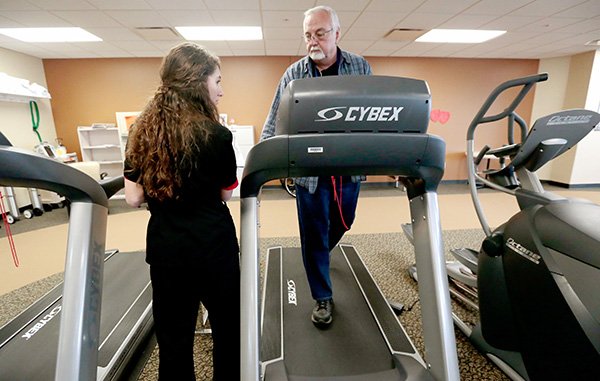 NWA Media/JASON IVESTER 
Exercise specialist Chelsey Humble talks to Gary Burney as he works out on one of the machines Wednesday inside the Cardiac Rehab Clinic at Mercy Hospital in Rogers. Symptoms of heart problems can include chest or upper body discomfort, shortness of breath, cold sweats, nausea and back or jaw pain.