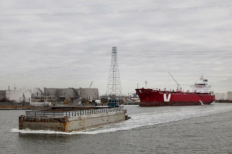 A towboat pushes a barge as a ship sits docked along the Houston Ship Channel in Houston, Texas, U.S., on Thursday, Jan. 30, 2014. As record oil and gas output floods the country with cheap and abundant energy and brings the U.S. closer to energy independence, the bulk of the fuels get squeezed through Houston, the country's largest export gateway and the core of its biggest refining region. Photographer: Scott Dalton/Bloomberg