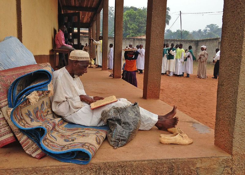In this photo taken on Sunday, Feb. 23, 2014, A Muslim man reads religions script at a Catholic church in Carnot a town 200 kilometers (125 miles) from the Cameroonian border, in, Central African Republic. The Christian militiamen knew hundreds of Muslims were hiding at the Catholic church and came with their ultimatum: Evict the families to face certain death or else the entire place would be burned to the ground.  (AP Photo/Steve Niko)