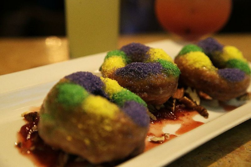 King cake doughnuts, served with strawberry jam and toasted pecan, are seen sat Emeril's Delmonico in New Orleans, Monday, Feb. 17, 2014. Attending a Mardi Gras parade may conjure up images of standing for hours among crowds of drunken revelry, street eats like hot dogs and cotton candy. That is one side of one of the biggest free parties in the world. But thereís another side to Mardi Gras _ for those willing to pay a little extra. Fine dining establishments along New Orleans parade routes offer a much different kind of experience.  (AP Photo/Gerald Herbert)