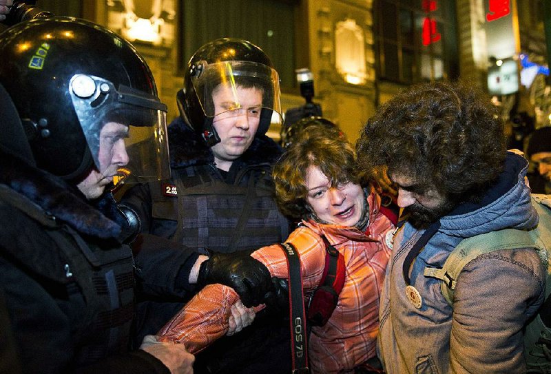 Russian police officers detain people in Manezhnaya Square, nest to Red Square during an unauthorized protest against the conviction of eight anti-government protesters in Moscow, Russia, Monday, Feb. 24, 2014, where hearings started against opposition activists detained on May 6, 2012 during a rally at Bolotnaya Square. Hundreds people, including a member of the punk band Pussy Riot who spent nearly two years in prison as punishment for their own anti-Putin protest, were detained by police. (AP Photo/Evgeny Feldman)