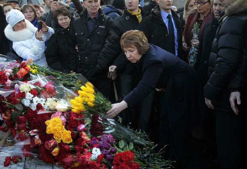 EU foreign policy chief Catherine Ashton places flowers at a memorial for the people killed in clashes with the police in central Kiev, Ukraine, Monday, Feb. 24, 2014. Ukraine's acting government issued an arrest warrant Monday for President Viktor Yanukovych, accusing him of mass crimes against the protesters who stood up for months against his rule. Russia sharply questioned its authority, calling it an "armed mutiny." (AP Photo/Sergei Chuzavkov)