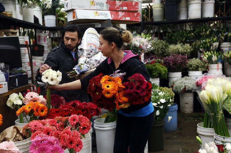 A customer (left) chooses flowers for his girlfriend on Valentine’s Day at the Flower Market in Los Angeles. Confidence in the economy among U.S. consumers fell more than forecast this month. 