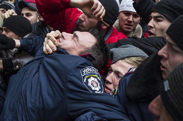 Crimean Tatars overwhelm a police officer Wednesday in Simferopol in Crimea as about 20,000 Muslim Tatar supporters of the interim Ukraine government clashed with a smaller group of pro-Russian ralliers. 