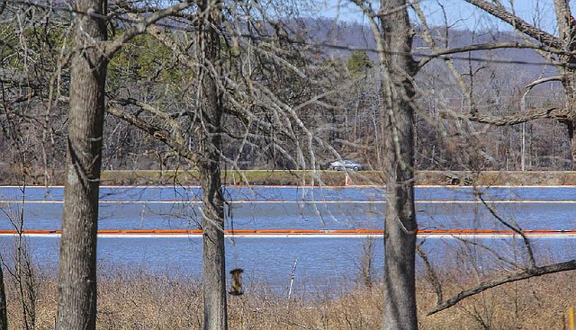 Multiple booms remain Wednesday in Dawson Cove along Arkansas 89 in Mayflower. Across the road lies the main body of Lake Conway, connected to the cove by culverts under the highway. 